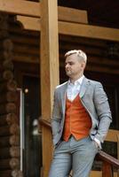 portrait of the groom in a gray suit and an orange vest photo