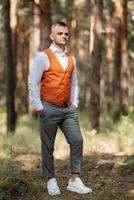 portrait of the groom in a gray suit and an orange vest photo