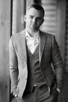 portrait of the groom in a gray suit and an orange vest photo