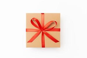 Flat lay of craft present box with red ribbon on the white background photo