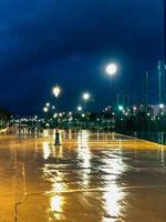 brillante gotas de lluvia y reluciente reflexiones en un tranquilo noche pasarela en el parque foto