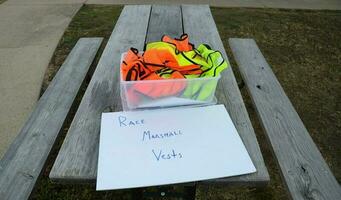 bucket of bright race marshall vests on table photo