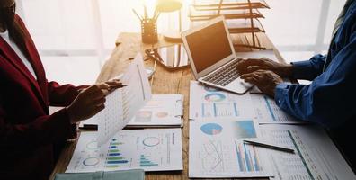 Group of confident business people point to graphs and charts to analyze market data, balance sheet, account, net profit to plan new sales strategies to increase production capacity. photo