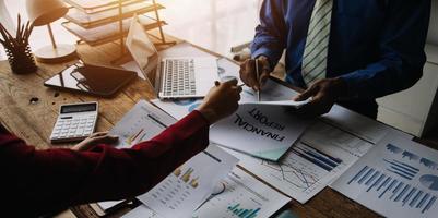 Group of confident business people point to graphs and charts to analyze market data, balance sheet, account, net profit to plan new sales strategies to increase production capacity. photo