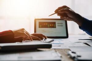 Group of confident business people point to graphs and charts to analyze market data, balance sheet, account, net profit to plan new sales strategies to increase production capacity. photo