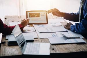 Group of confident business people point to graphs and charts to analyze market data, balance sheet, account, net profit to plan new sales strategies to increase production capacity. photo