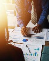 Group of confident business people point to graphs and charts to analyze market data, balance sheet, account, net profit to plan new sales strategies to increase production capacity. photo