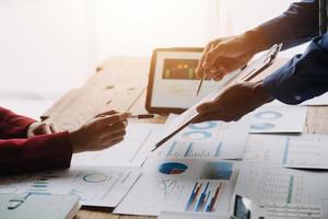 Group of confident business people point to graphs and charts to analyze market data, balance sheet, account, net profit to plan new sales strategies to increase production capacity. photo