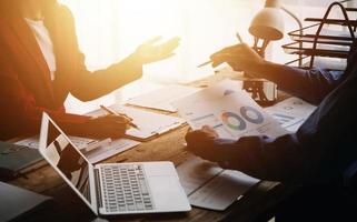 Group of confident business people point to graphs and charts to analyze market data, balance sheet, account, net profit to plan new sales strategies to increase production capacity. photo