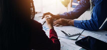 Group of confident business people point to graphs and charts to analyze market data, balance sheet, account, net profit to plan new sales strategies to increase production capacity. photo