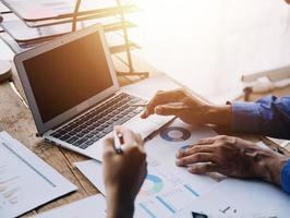 Group of confident business people point to graphs and charts to analyze market data, balance sheet, account, net profit to plan new sales strategies to increase production capacity. photo