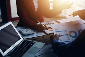 Group of confident business people point to graphs and charts to analyze market data, balance sheet, account, net profit to plan new sales strategies to increase production capacity. photo