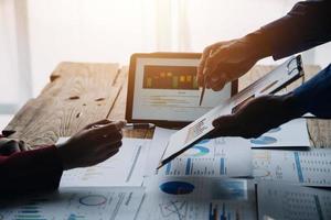 Group of confident business people point to graphs and charts to analyze market data, balance sheet, account, net profit to plan new sales strategies to increase production capacity. photo