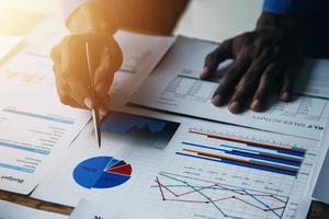 Group of confident business people point to graphs and charts to analyze market data, balance sheet, account, net profit to plan new sales strategies to increase production capacity. photo