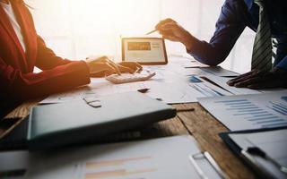 Group of confident business people point to graphs and charts to analyze market data, balance sheet, account, net profit to plan new sales strategies to increase production capacity. photo