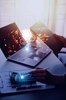 The hand of a man with a light bulb And there is a gear icon in it And he is using a notebook computer photo
