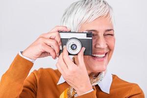 Mature female photographer taking pictures with old retro camera. Professional photographer doing a photoshoot. photo