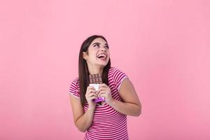 Portrait of a pretty young girl eating chocolate bar isolated over pink background. Satisfied pretty girl biting chocolate bar photo