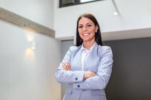 Portrait of happy mature businesswoman standing with her arms crossed. adult female looking at camera and smiling while standing in office. photo