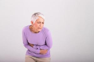 Unhealthy mature woman holding belly, feeling discomfort, health problem concept, unhappy older female sitting on bed, suffering from stomachache, food poisoning, gastritis, abdominal pain, climax photo