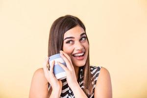 Coffee lover concept. Closeup photo portrait of delightful cheerful positive with toothy beaming smile person holding cup of warm latte in hands cuddling to herself isolated bright color background