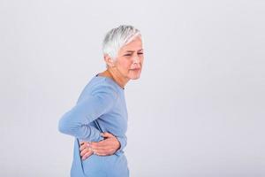 Elderly woman with gray hair touching her aching hip. Upset mature old woman touching back feel hurt osteoarthritis kidney spine ache sore muscles, sad senior lady suffer from lower lumbar pain photo