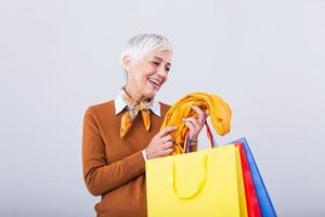 Happy mature good looking woman happy with her purchase, holding silk scarf looking at it and smiling. Shopping concept photo