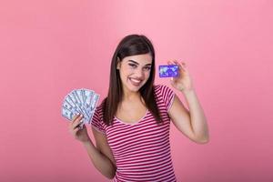 Young beautiful woman shopper holding credit card and dollar fan cash banknotes. Financial banking concept photo