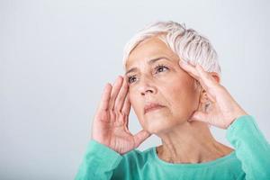 mujer que sufre de estrés o dolor de cabeza haciendo muecas de dolor. anciana con migraña sintiéndose mal. retrato de una atractiva anciana con dolor de cabeza, sintiendo dolor foto