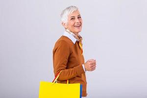 retrato de un contento maduro mujer participación compras pantalones y mirando a cámara aislado terminado blanco antecedentes foto