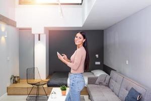 Smart home technology interface on smart controler app screen with augmented reality view of internet of things connected objects in the apartment interior, person holding device photo