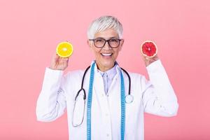 Happy dietitian nutritionist holding grapefruit and orange having fun. Woman promoting healthy food fruit. Right eating nutrition and slimming concept. photo