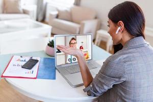 Businesswoman making video call to her doctor using laptop. Back view of woman making video call with her doctor while staying at home. photo