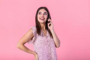 Beautiful teen woman talking on cellphone, making happy surprice face, studio shot. Portrait of a pretty joyful girl in dress talking on mobile phone photo