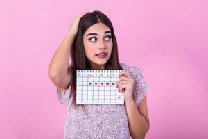 joven caucásico mujer participación menstruación calendario terminado aislado antecedentes asustado en conmoción con un sorpresa rostro, temeroso y emocionado con temor expresión foto