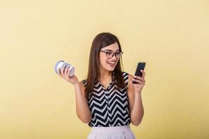 joven inteligente exitoso mujer en lentes teniendo romper, participación café a Vamos y surf el Internet con su móvil inteligente teléfono foto