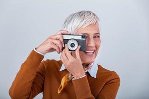 Mature female photographer taking pictures with old retro camera. Professional photographer doing a photoshoot. photo