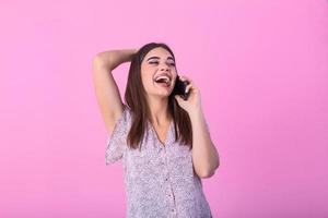 Beautiful teen woman talking on cellphone, making happy surprice face, studio shot. Portrait of a pretty joyful girl in dress talking on mobile phone photo
