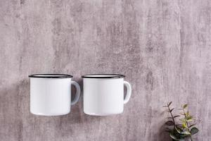 Two white empty metal mugs on a gray background with a place for an inscription. Top view photo