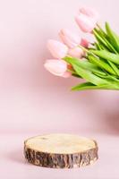 Vertical natural mock-up of a tree cut on a pink background with a bouquet of tulips photo