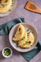 Tortillas stuffed with mashed potatoes and onions on a plate. Top and vertical view photo