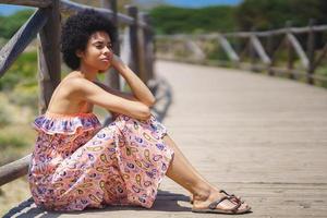 Thoughtful black woman sitting on boardwalk photo