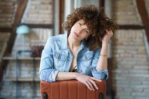 Pensive woman sitting on chair and touching curly hair photo