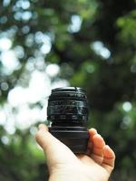 camera lens on hand with green nature background