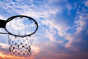 Basketball hoop viewed from below on beautiful sky background, A view of a basketball hoop from below photo