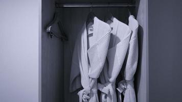 three bathrobe hanging on rack in wardrobe at hotel room photo
