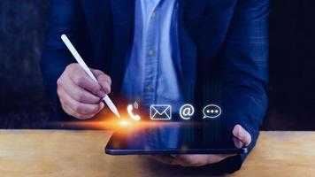 Contact us or Customer support hotline people connect. Businessman using showing and touching on virtual screen contact icons call phone, email, address, live chat, photo