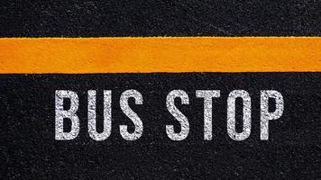autobús detener texto escrito y amarillo línea en el la carretera en medio de el asfalto camino, autobús detener palabra en calle. foto