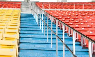 asientos vacíos de color naranja y amarillo en el estadio, filas de asientos en un estadio de fútbol foto