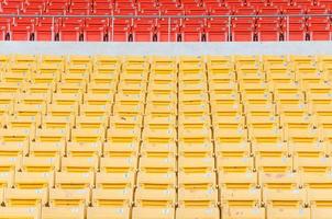 asientos vacíos de color naranja y amarillo en el estadio, filas de asientos en un estadio de fútbol foto